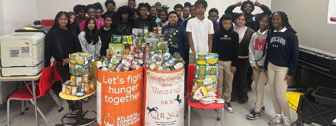 Students posing with canned foods from can food drive.